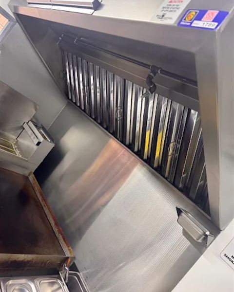 Stainless commercial kitchen hood over a cooking line