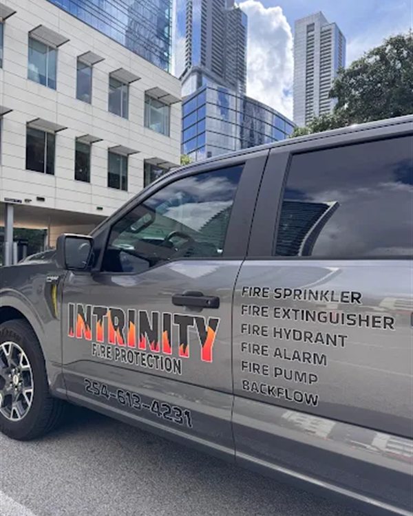 Intrinity Fire Protection service truck in downtown Austin, lettered with its sprinkler, extinguisher, hydrant, alarm, pump, and backflow services