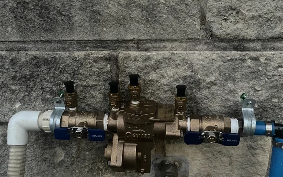 Brass reduced pressure backflow assembly with test cocks mounted on a stone wall