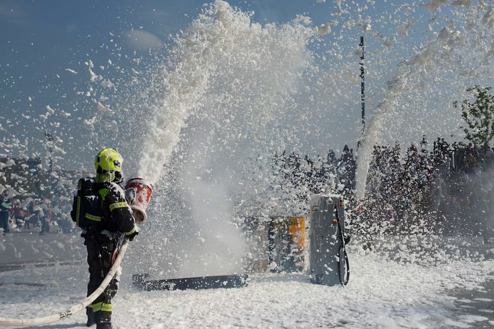 Firefighter discharging fire suppression foam during a live demonstration