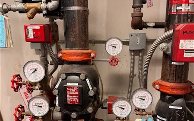 Sprinkler riser room with alarm valves, gauges, and service tags